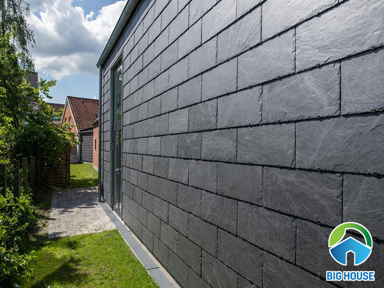 Ốp tường vườn sau nhà bằng gạch thẻ giả đá màu xám đen.
